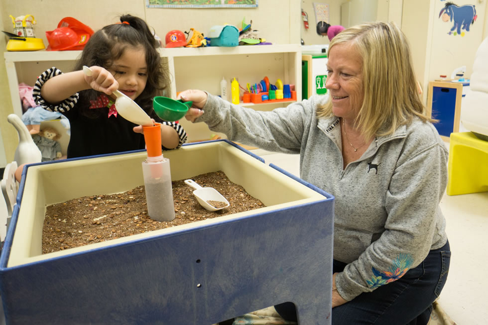 Teacher and preschooler playing with dirt